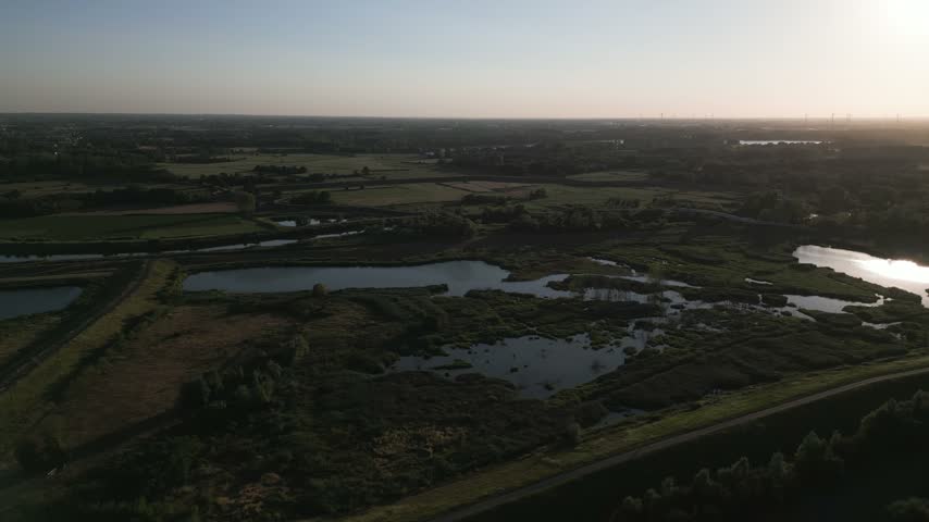 Swampy landscape near Mechelen Belgium with reflective water and setting sun in natural surroundings