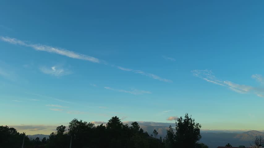 Slow Pan of Wispy Clouds Over Mountain Tree Silhouettes.