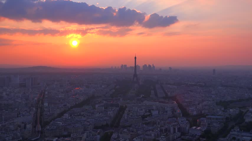 Panoramic drone footage of Paris skyline at sunset. Eiffel Tower landmark with vibrant sky and clouds.