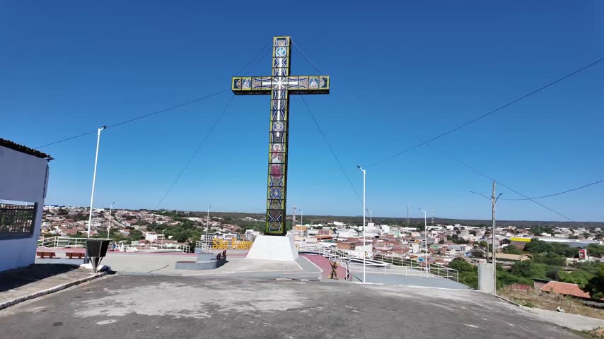 Towering stained glass cross monument overlooks hilltop skate plaza and rooftops of Sao Raimundo Nonato Brazil