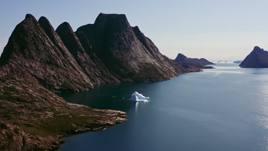 Aerial Greenland Fjord Landscape with Lone Iceberg, Calm Arctic Water and Dramatic Coastal Mountains