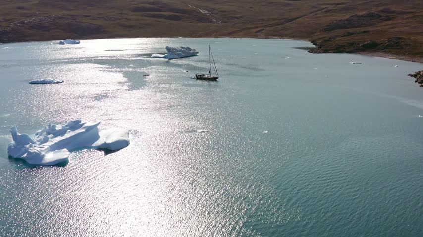 Aerial Dolly In Over Sailboat Among Icebergs in Remote Greenland Arctic Coastal Landscape