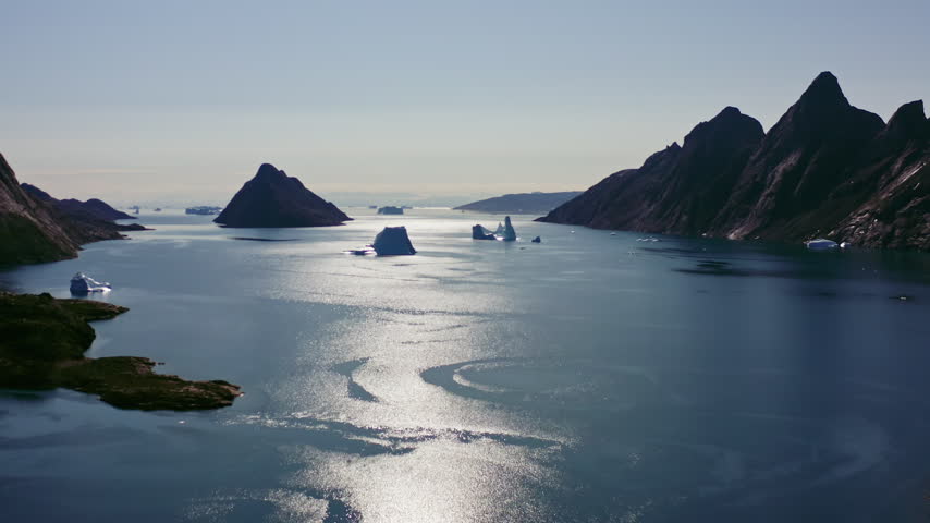 Aerial Wide Establishing View of Greenland Fjord with Icebergs and Dramatic Arctic Mountain Landscape