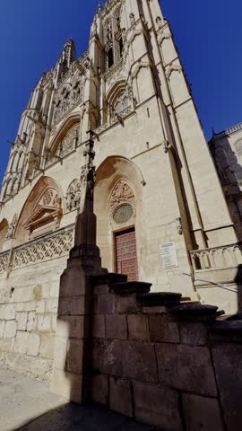 Low angle view moving down along the majestic Gothic facade of the Cathedral of Saint Mary of Burgos on a clear sunny day in Spain