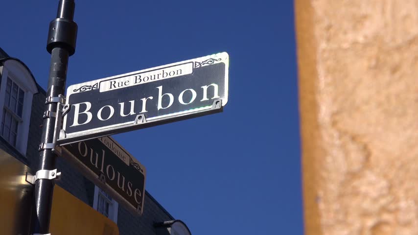 Historical street name signage Rue Bourbon against clear blue sky in famous New Orleans tourist destination travel footage.