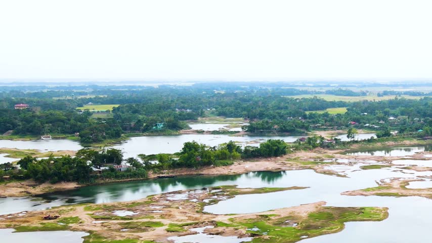 Small village landscape surrounded by dry braided river with trees in Asia - aerial.