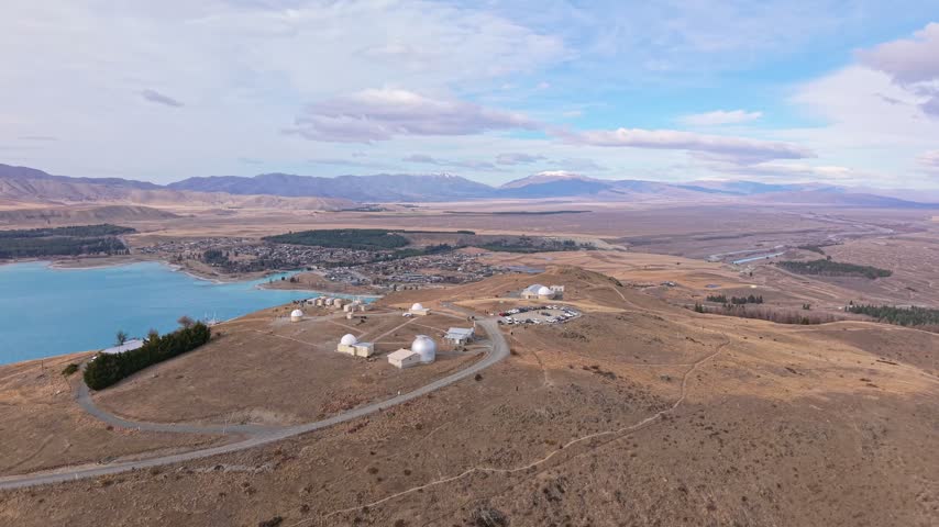 Aerial view rising over Mt John Observatory and Lake Tekapo with distant mountains