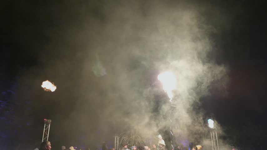 Flames shoot from towers during a night fire show at an outdoor festival event