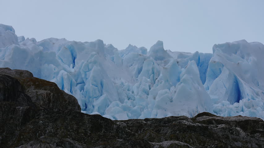 Blue Glacier Ice Behind Rocky Hill, Icefield in Antarctica, Close Up
