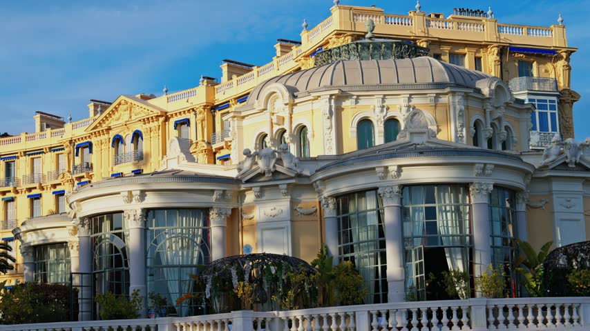Footage capturing elegant architecture of historic luxury hotel building under blue sky in Monaco.