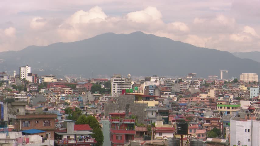 Kathmandu city skyline and mountains in a wide establishing shot of the urban landscape in Nepal. Dense residential architecture and sprawling metropolitan development
