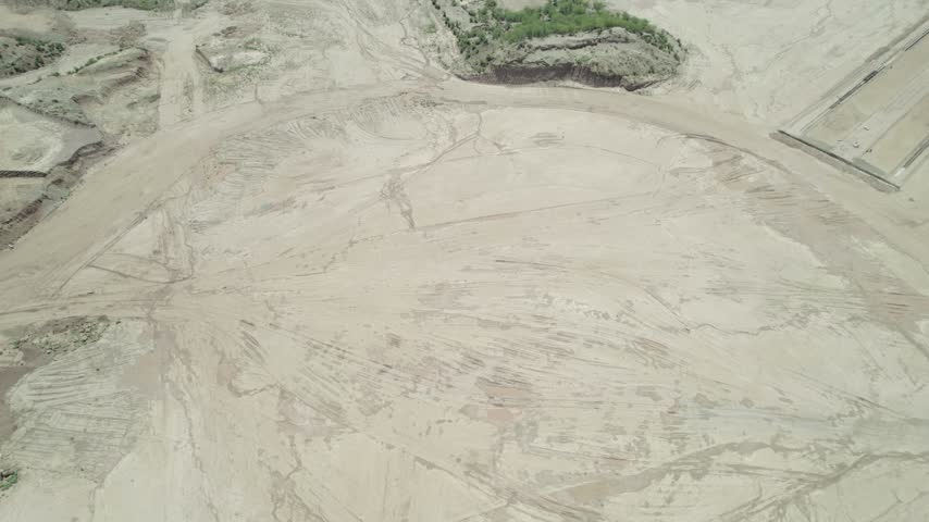Large cleared earthwork area shows graded soil, vehicle tracks and sparse vegetation