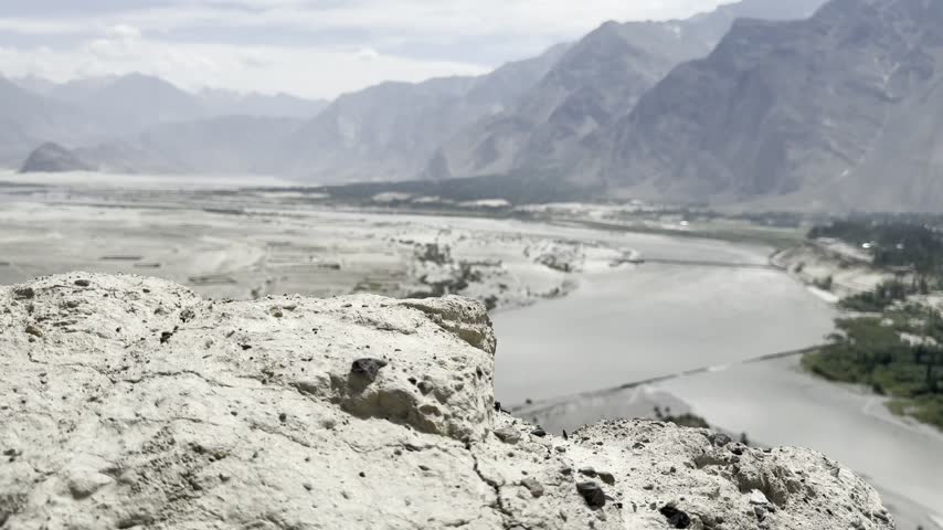 Broad river channels wind through a sandy mountain valley beneath steep peaks in Skardu, Pakistan