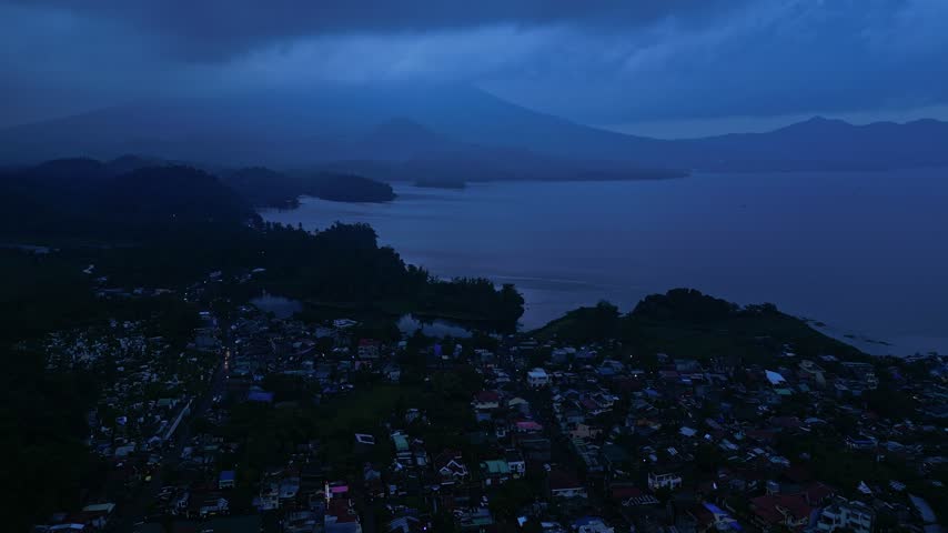 Aerial view over Buhi town and Lake Buhi at dusk in Camarines Sur, Philippines, with Mount Asog, also known as Mount Iriga, in the background. Santa Cruz barangay is visible in the distant landscape.