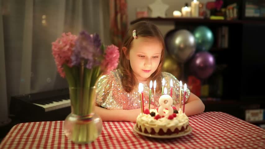 Little girl blowing out birthday candles and making a wish during her eighth birthday celebration at home
