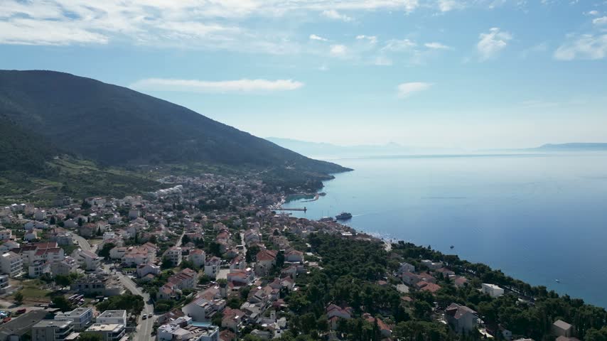 Aerial timelapse over a Croatian town on Brač Island, showing the harbour receiving and dispatching boats against a beautiful Adriatic coastal setting.