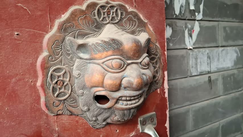 Close up of an ancient stone lion sculpture on a wall. Traditional decorative carving, cultural heritage, historic architecture. China, Beijing.