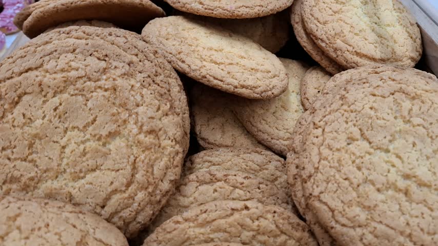 Close up view of freshly baked sweet biscuits displayed at a bakery shop counter. Homemade delicious treats, crispy pastry cookies, confectionery dessert snack.