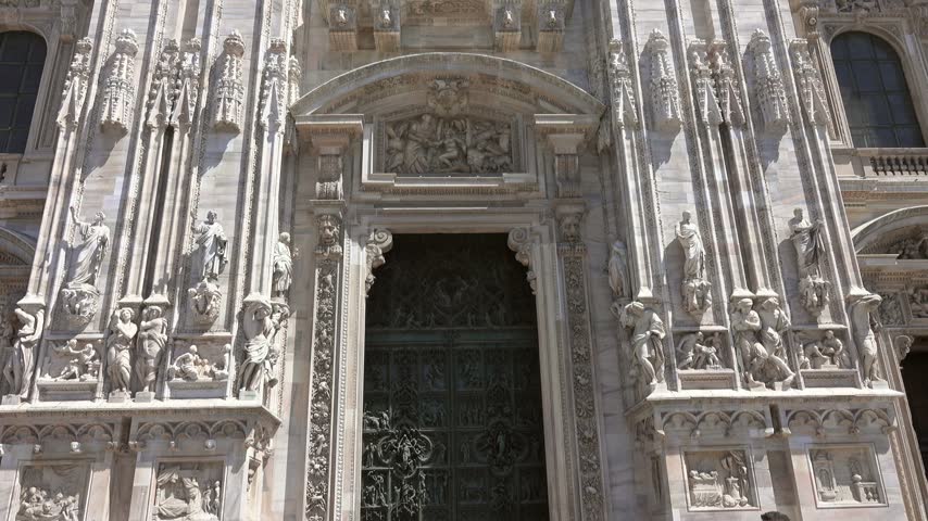 View of the intricate marble facade and gothic sculptures of the Duomo di Milano in Milan, Lombardy, Italy.