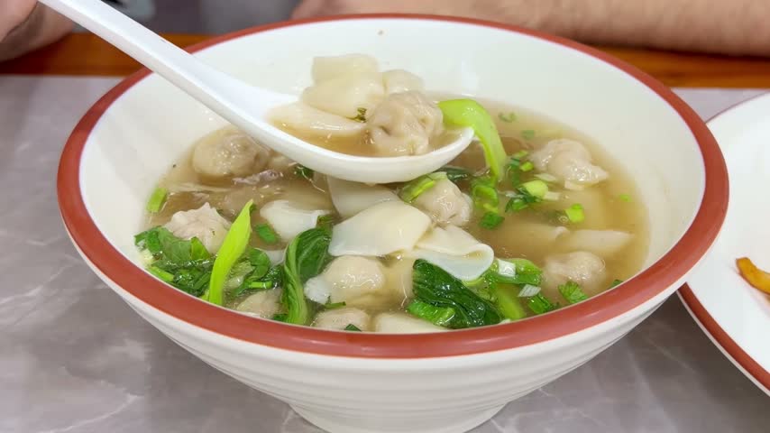 Close Up of Chinese Wontons on Restaurant Table – Traditional Dumpling Soup with Green Onions	

