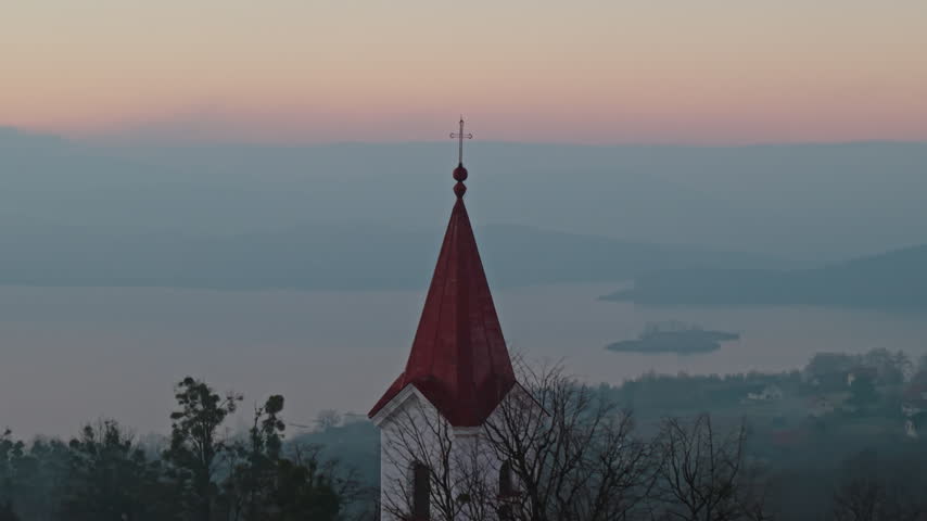 St. Adalbert Church spire against Mucharskie Lake at twilight, Poland