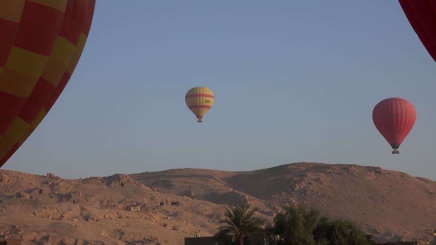 View of hot air balloons floating over the desert landscape in Luxor Governorate, Egypt.