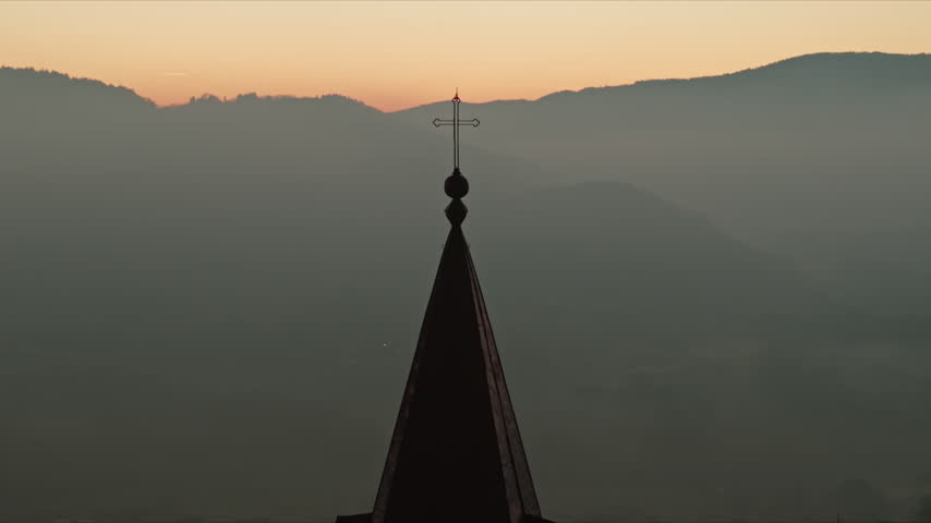Aerial reveal of St. Adalbert Church steeple against twilight mountains, Poland
