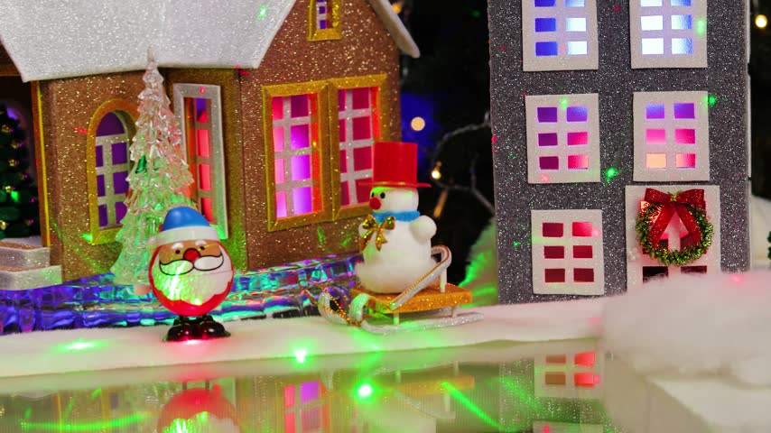 In the center of the Christmas village, a yellow car pulls up to a gray little house adorned with small fir trees and snowmen