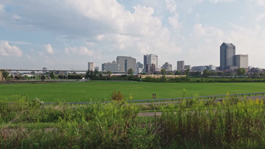 2026 drone video of Columbus OH skyline towers and buildings along new highway i70 east west cas with traffic on roadway by Ohio capital city downtown hub and business district and Audubon center park 4k