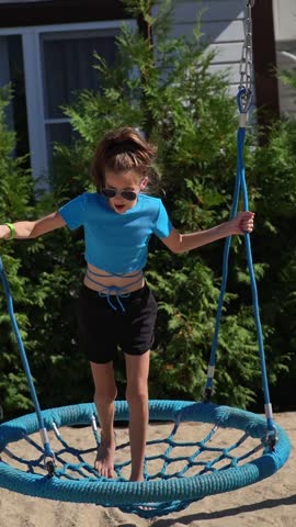 A teenage girl with an electronic key bracelet and sunglasses is relaxing in a hammock.