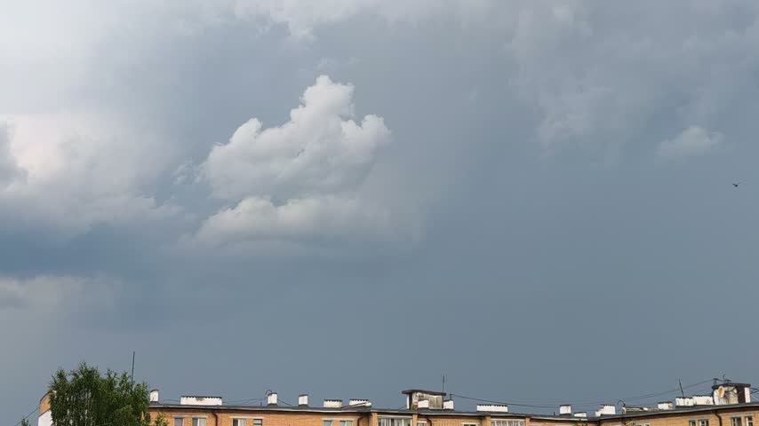 A brief lightning discharge against dense storm clouds above an urban neighborhood. High-quality atmospheric footage of severe weather. Storm Clouds and Lightning Strike Above the City.