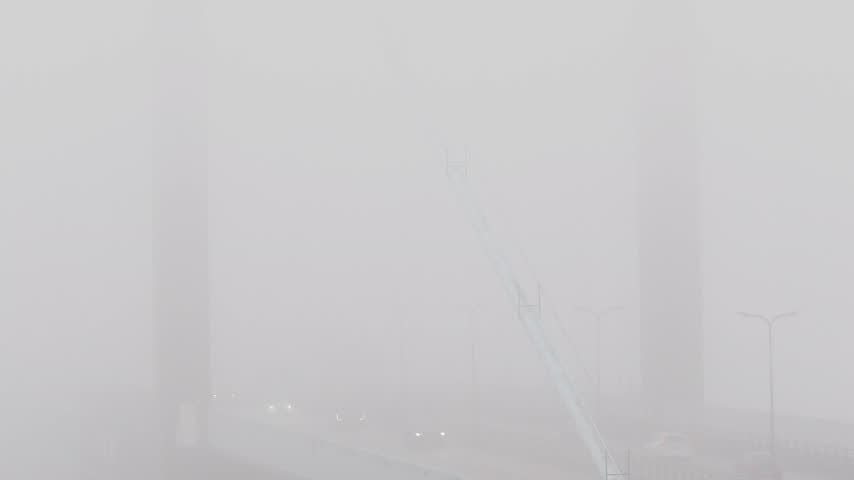 View of Alvsborgsbron bridge shrouded in heavy fog with faint car lights visible on the road in Goteborg, Vastra Gotalands lan, Sweden.
