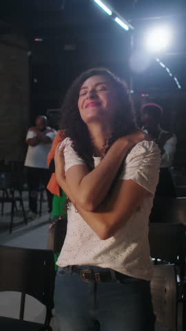 Female parishioner worshiping with closed eyes and arms crossed over shoulders in chapel expressing spiritual joy, heartfelt faith, and inner healing