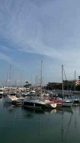 Vertical shot of pleasure boats moored along the marina pontoon with the town behind in Gandia, Spain.