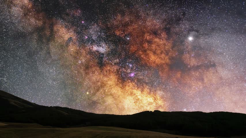 Bright colorful close-up milky way galaxy on the night sky over the hill and meadow.