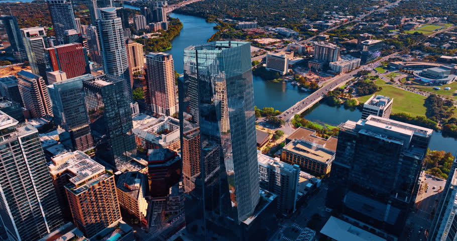 Glass skyscraper of unusual shape in the downtown of Houston, Texas, USA. Cars go by the bridges over the Colorado River crossing the city.