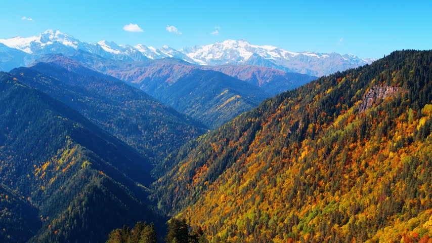 Hazy mountain landscape covered with woods and some snow. Drone flight over the stunning autumn Caucasian Mountains in Georgia.