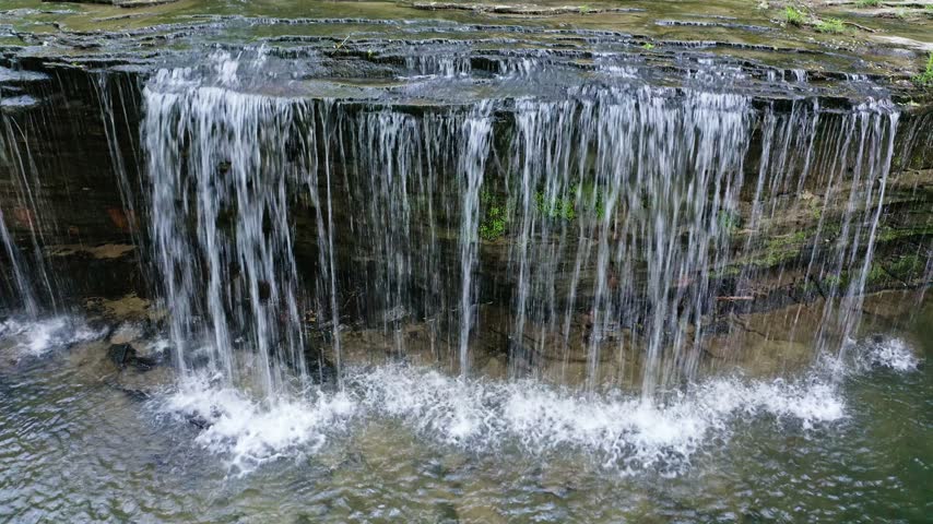High angle view of Princess Falls and its broad sandstone ledge surrounded by dense late-spring forest in Daniel Boone National Forest in the Big South Fork region of southern Kentucky