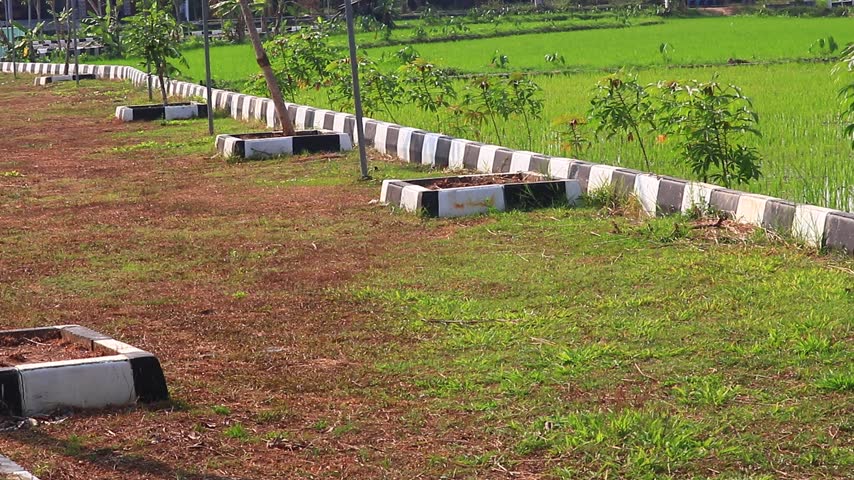 Wide view of a rural fence line with alternating posts and rails beside green fields and open countryside under daylight.
