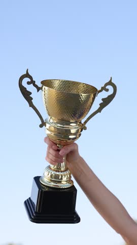 Woman with gold trophy cup outdoors, low angle view. Slow motion effect