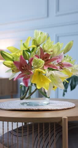 Bouquet of beautiful lilies in vase on table indoors