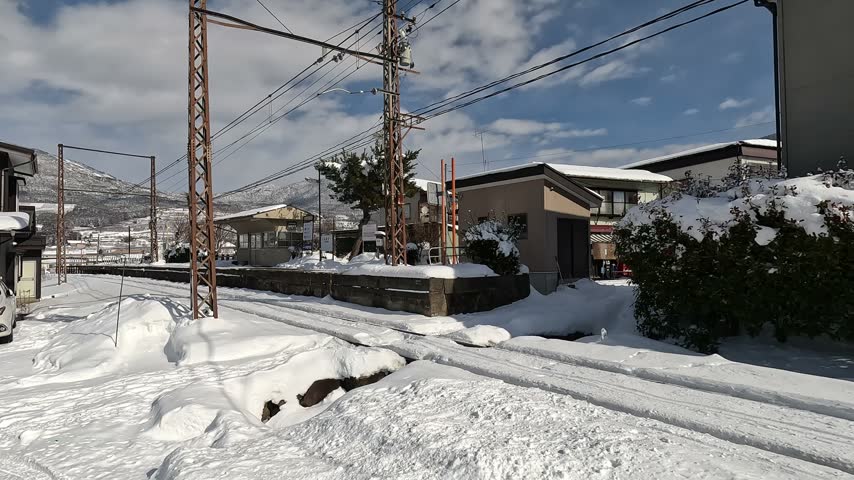 Snow-covered platform and waiting room of a local train station under a clear blue sky in winter, Japan