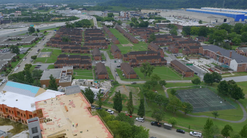 Drone view of brick townhome rows and a tennis court in a Chattanooga, Tennessee neighborhood, with construction underway nearby.