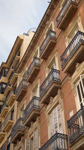 Upward perspective of colorful urban apartment building facade featuring detailed architectural design and wrought iron railings.