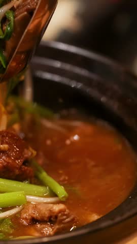 Hot Thai beef soup with morning glory and bean sprouts cooked in a clay pot.