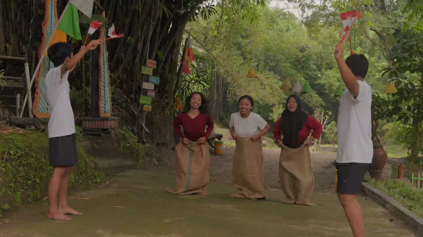 Excited young Indonesian people wearing gunny sack and jumping, joining competition. Indonesia Independence Day concept.