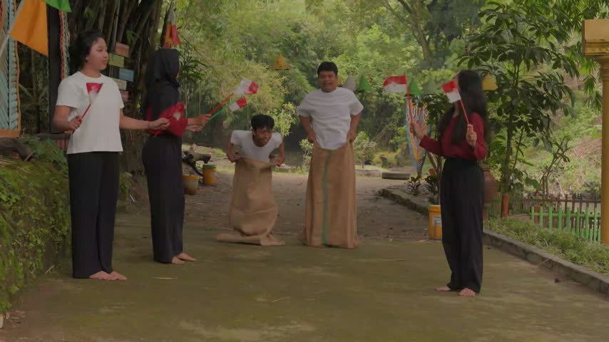 Excited young Indonesian people wearing gunny sack and jumping, joining competition. Indonesia Independence Day concept.