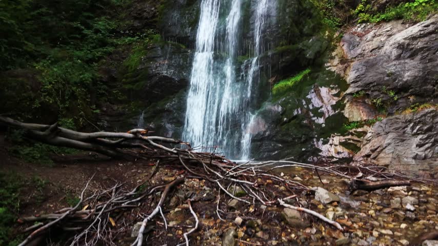 A tranquil waterfall cascades down rocky cliffs amidst vibrant greenery,A tranquil waterfall cascading into lush greenery
