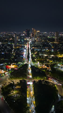 Aerial night timelapse of Surabaya, Indonesia, showing busy traffic along a major city road, illuminated buildings and an expansive urban skyline in East Java.