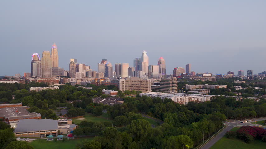 Drone footage of charlotte north carolina early sunset time going from bottom to top over looking the whole city. the skyline is also lit up in red white and blue to celebrate 4th of july